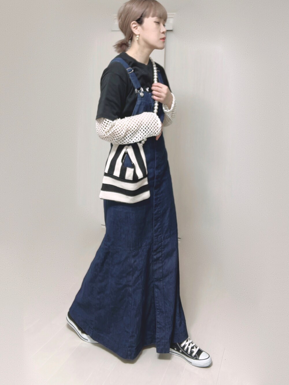ブルー系のジャンパースカート、ブラック系のTシャツ/カットソー、ホワイト系のショルダーバッグを着用したレディースの春コーディネートの2枚目の写真