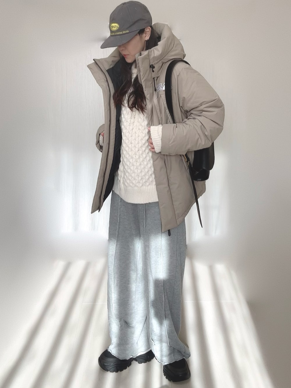 ベージュ系のダウンジャケット/コート、グレー系のスウェットパンツ、ホワイト系のニット/セーターを着用したレディースの冬コーディネートの3枚目の写真