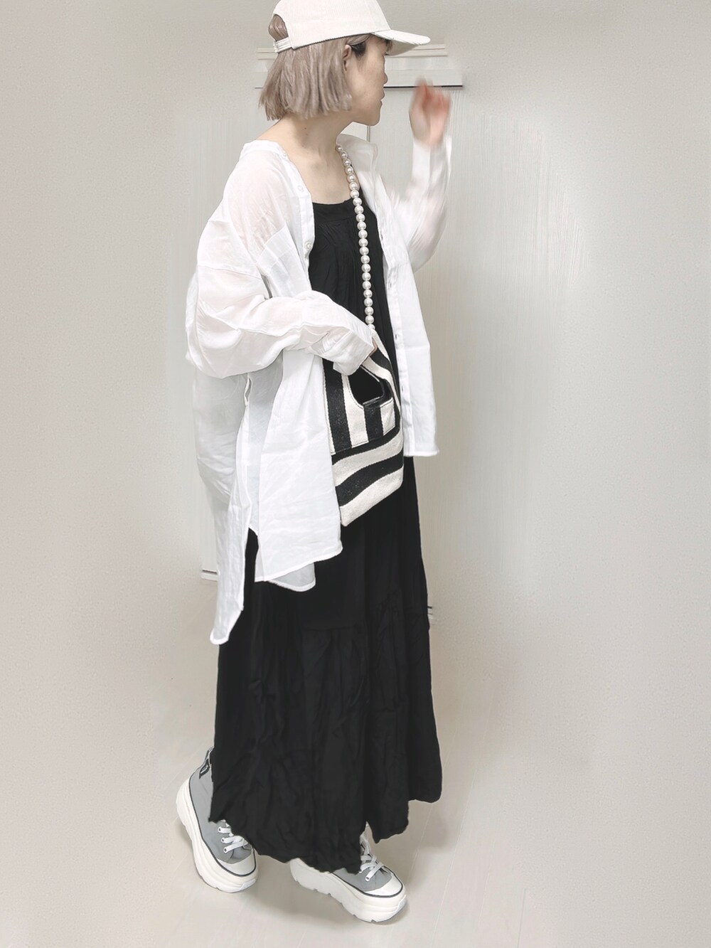 ブラック系のワンピース、ホワイト系のシャツ/ブラウス、ホワイト系のショルダーバッグを着用したレディースの春コーディネートの2枚目の写真