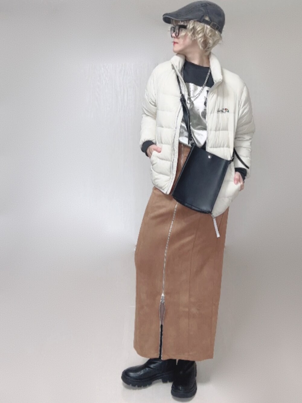 ブラック系のブーツ、ホワイト系のダウンジャケット/コート、ブラック系のショルダーバッグを着用したレディースの秋コーディネートの4枚目の写真
