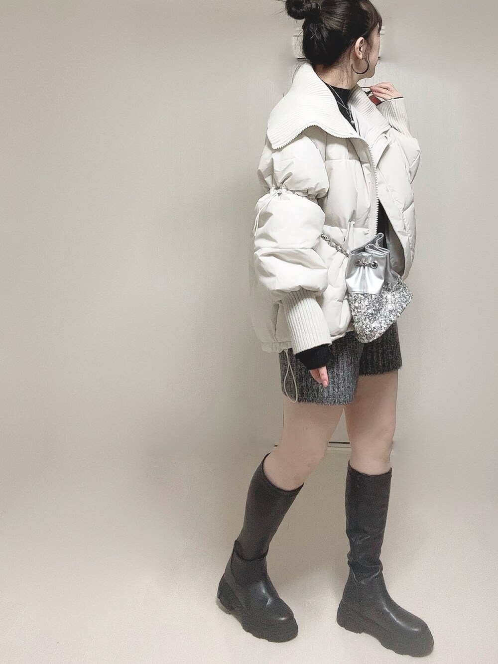 ホワイト系のダウンジャケット/コート、ブラック系のニット/セーター、ブラック系のブーツを着用したレディースの冬コーディネートの2枚目の写真