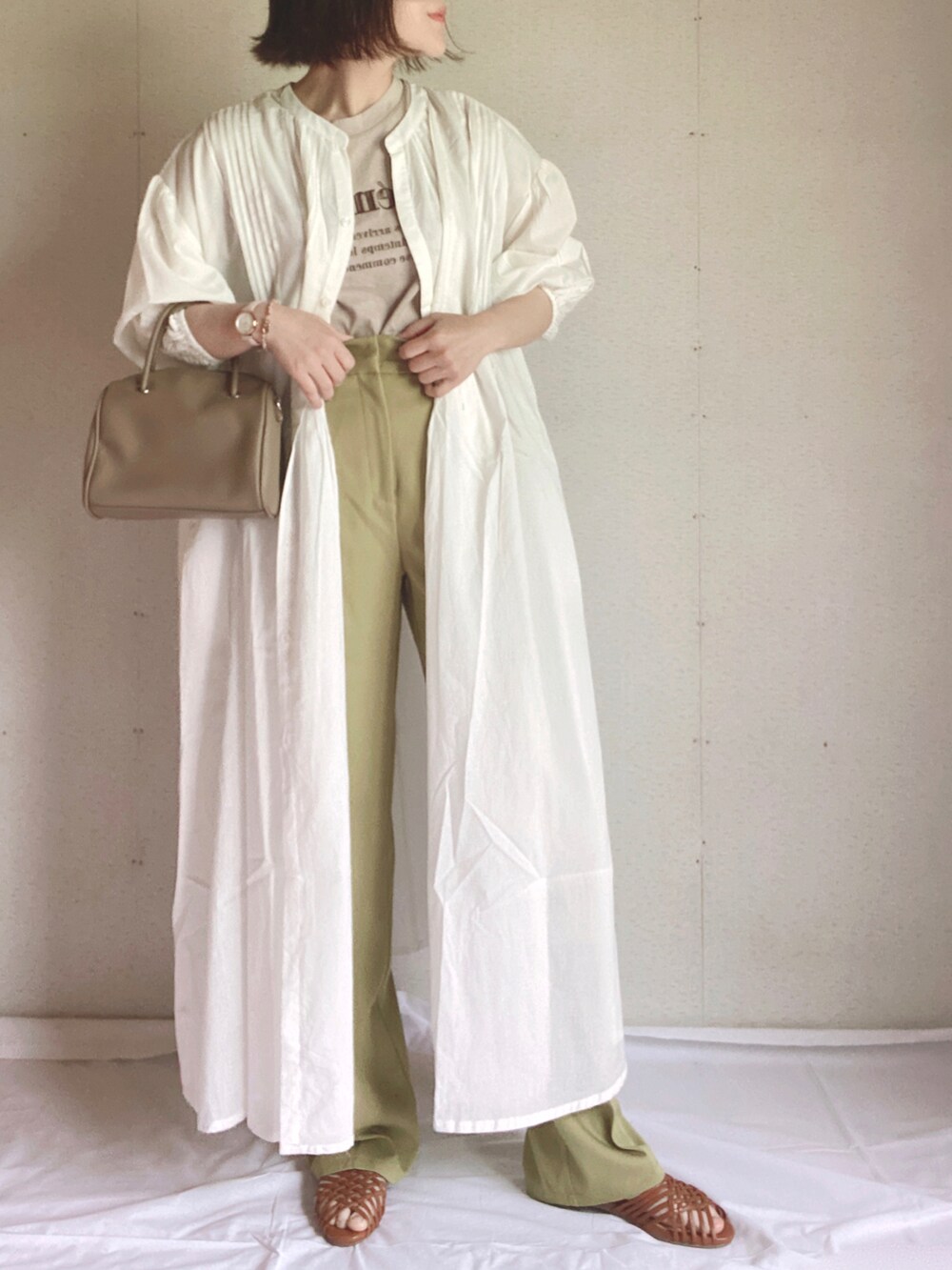 グリーン系のスラックス、ホワイト系のシャツワンピース、ブラウン系のサンダルを着用したレディースの夏コーディネートの2枚目の写真