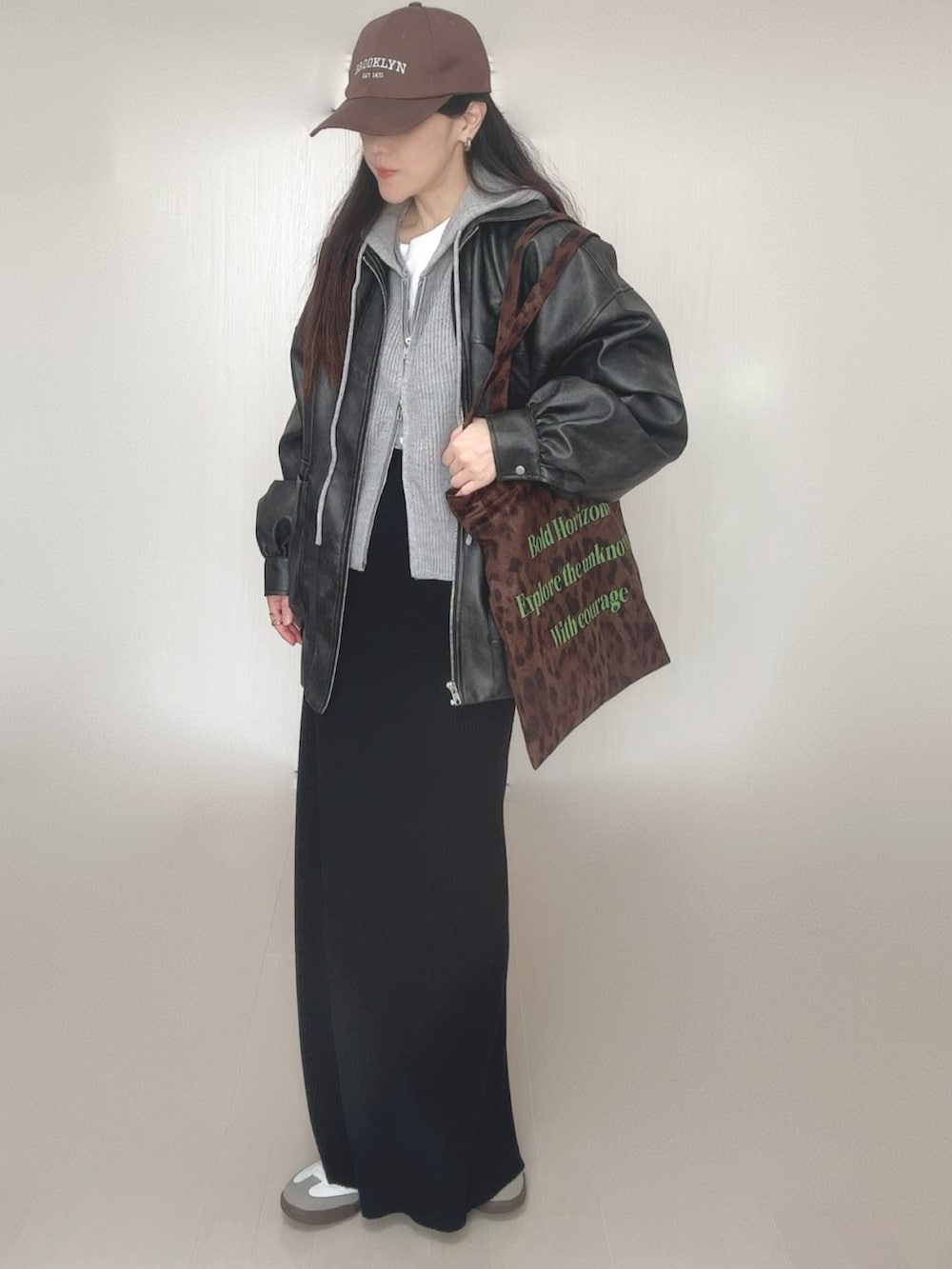 グレー系のパーカー、ブラック系のブルゾン、ブラウン系のトートバッグを着用したレディースの冬コーディネートの4枚目の写真