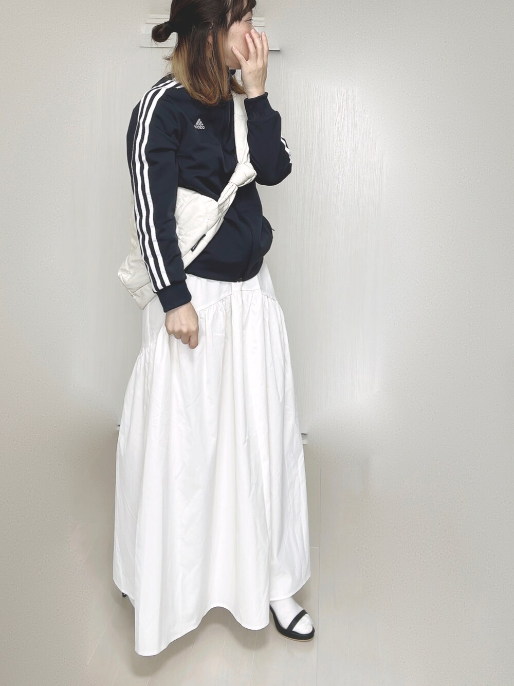 ブルー系のナイロンジャケット、ホワイト系のショルダーバッグ、ホワイト系のスカートを着用したレディースの秋コーディネートの2枚目の写真