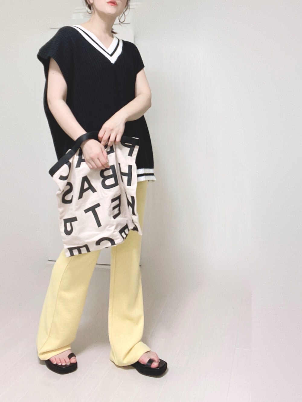 イエロー系のその他パンツ、ブラック系のベスト、ホワイト系のトートバッグを着用したレディースの夏コーディネートの3枚目の写真