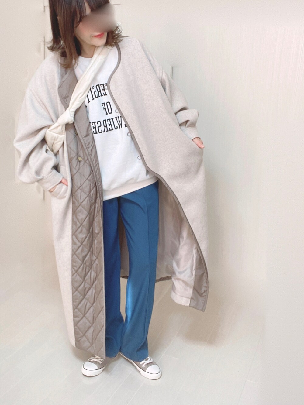 ベージュ系のノーカラーコート、ホワイト系のスウェット、ブルー系のその他パンツを着用したレディースの冬コーディネートの3枚目の写真