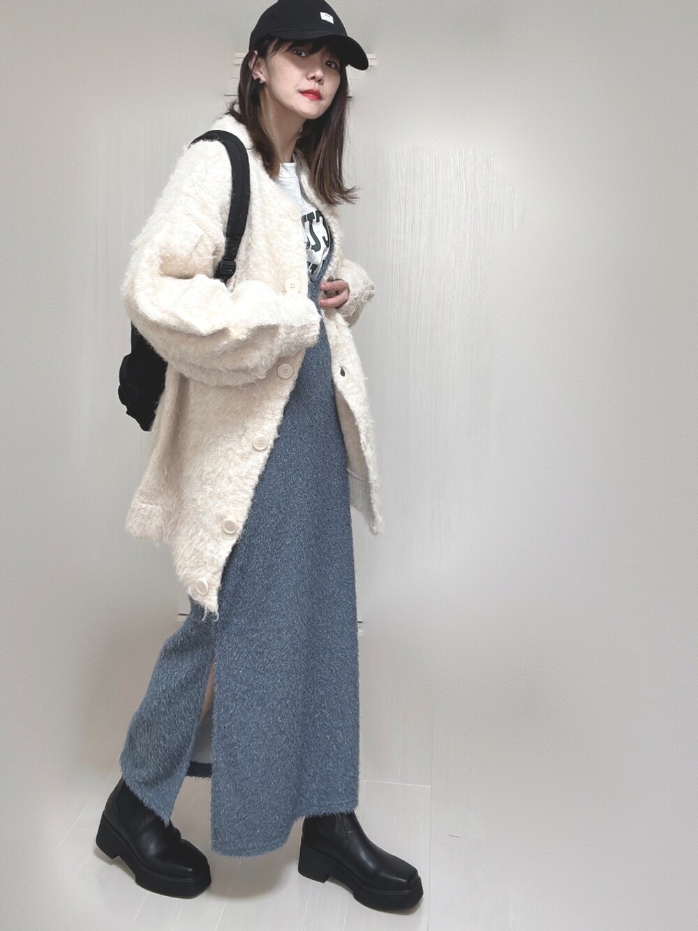 ベージュ系のカーディガン/ボレロ、ブラック系のブーツ、ブラック系のバックパック/リュックを着用したレディースの秋コーディネートの2枚目の写真