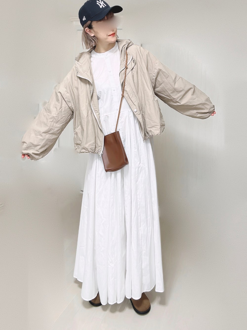 ベージュ系のマウンテンパーカー、ホワイト系のシャツワンピース、ブラウン系のショルダーバッグを着用したレディースの春コーディネートの3枚目の写真