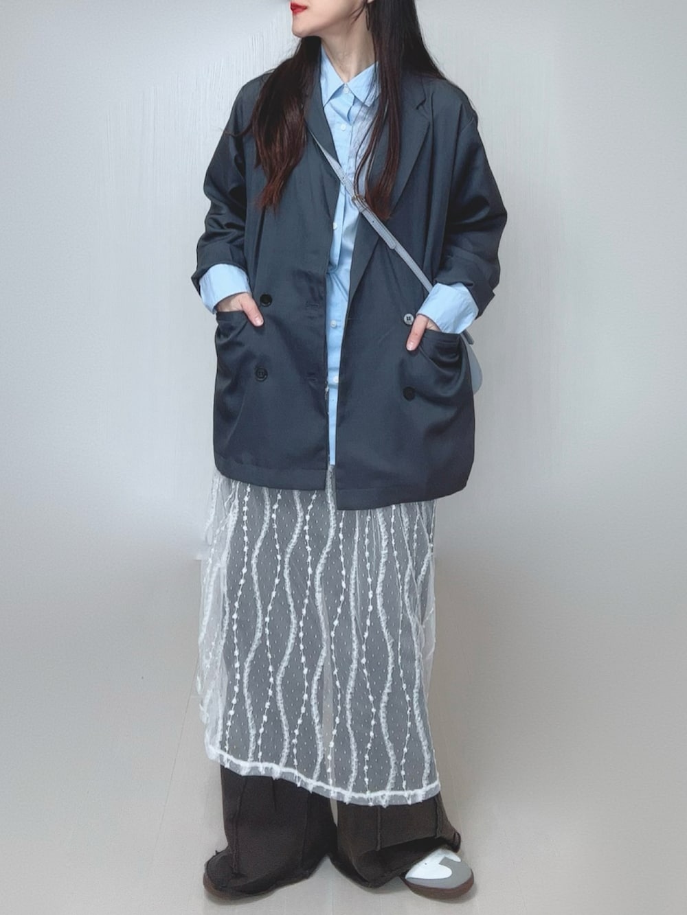 グレー系のテーラードジャケット、ブラック系のスウェットパンツ、ホワイト系のスカートを着用したレディースの春コーディネートの5枚目の写真