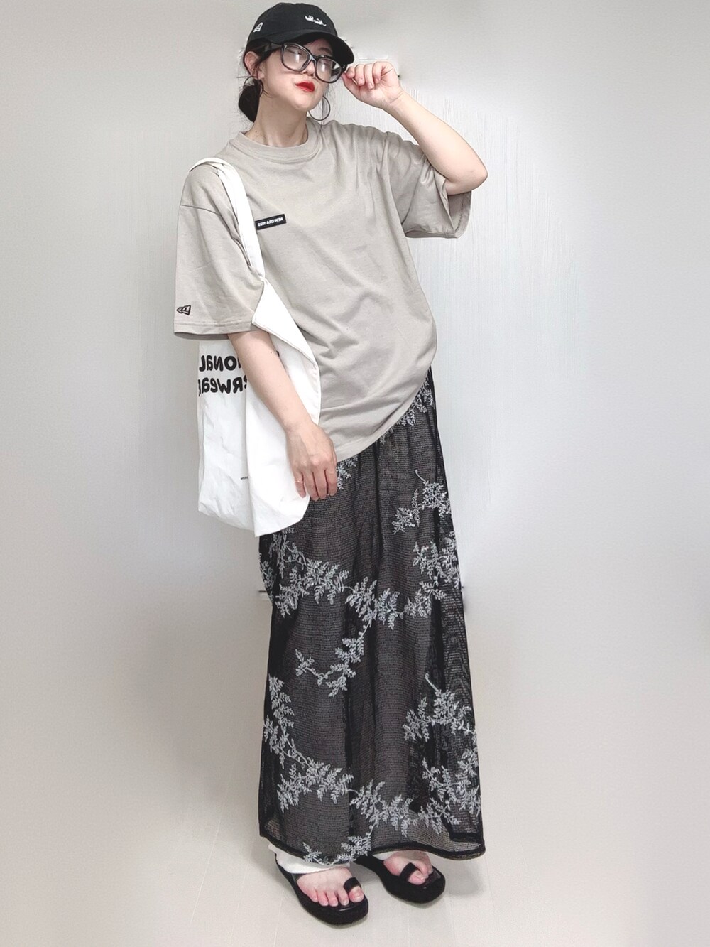 ブラック系のワンピース、ブラック系のサンダル、ベージュ系のTシャツ/カットソーを着用したレディースの夏コーディネートの3枚目の写真