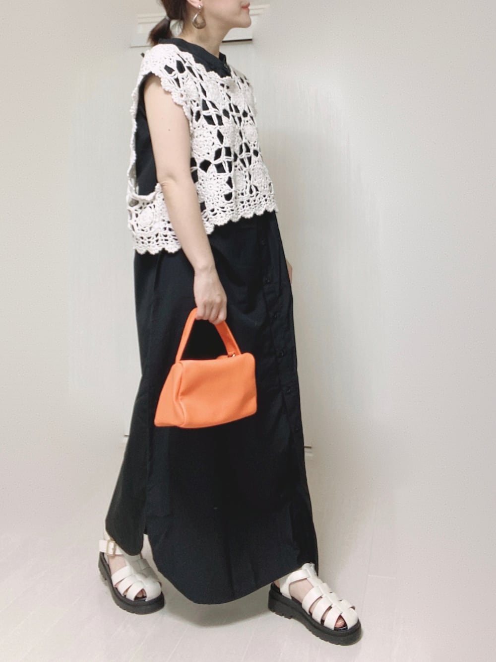 ブラック系のワンピース、オレンジ系のショルダーバッグを着用したレディースの夏コーディネートの2枚目の写真