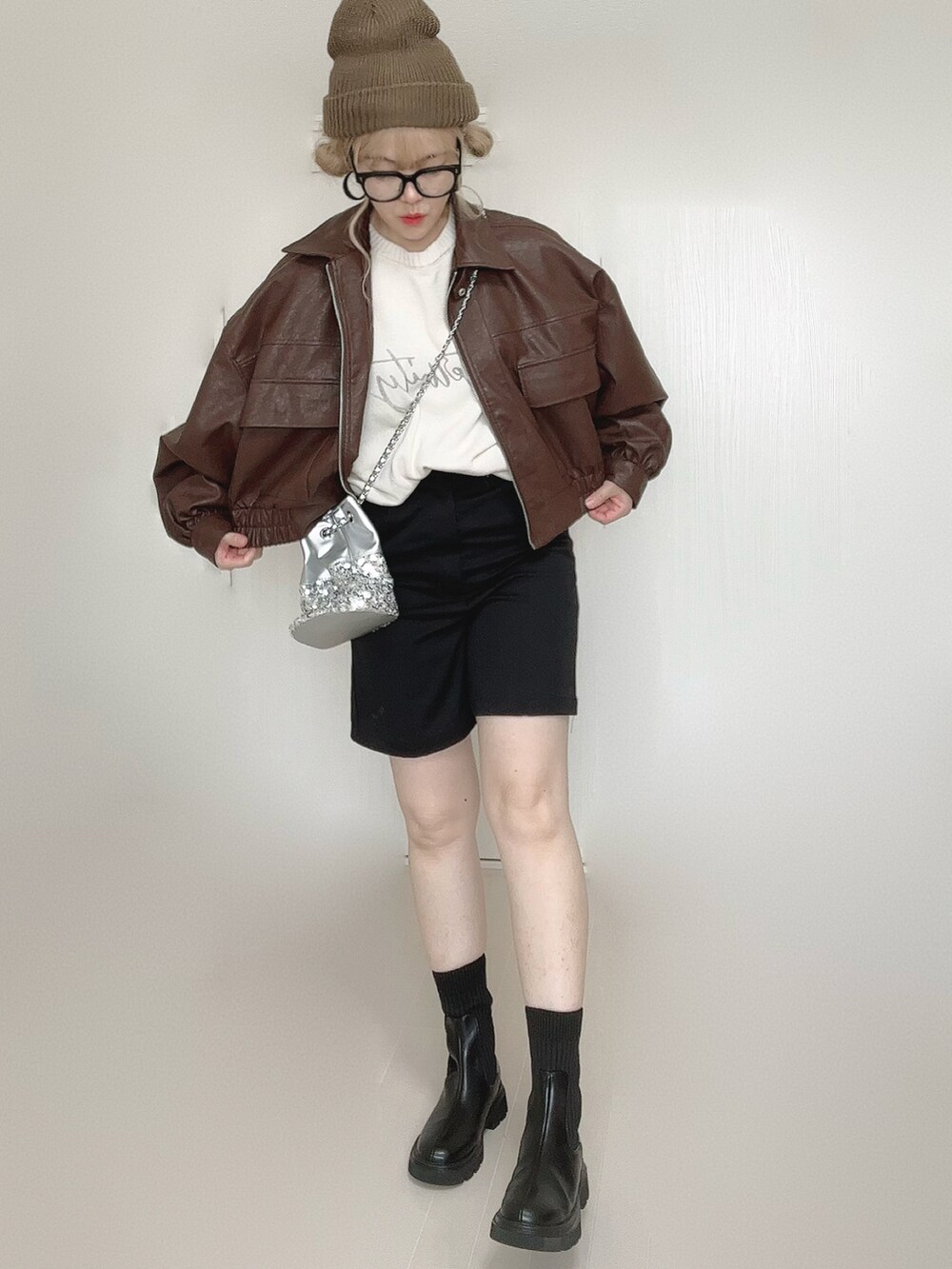 ブラウン系のブルゾン、ホワイト系のニット/セーター、ブラック系のブーツを着用したレディースの秋コーディネートの3枚目の写真