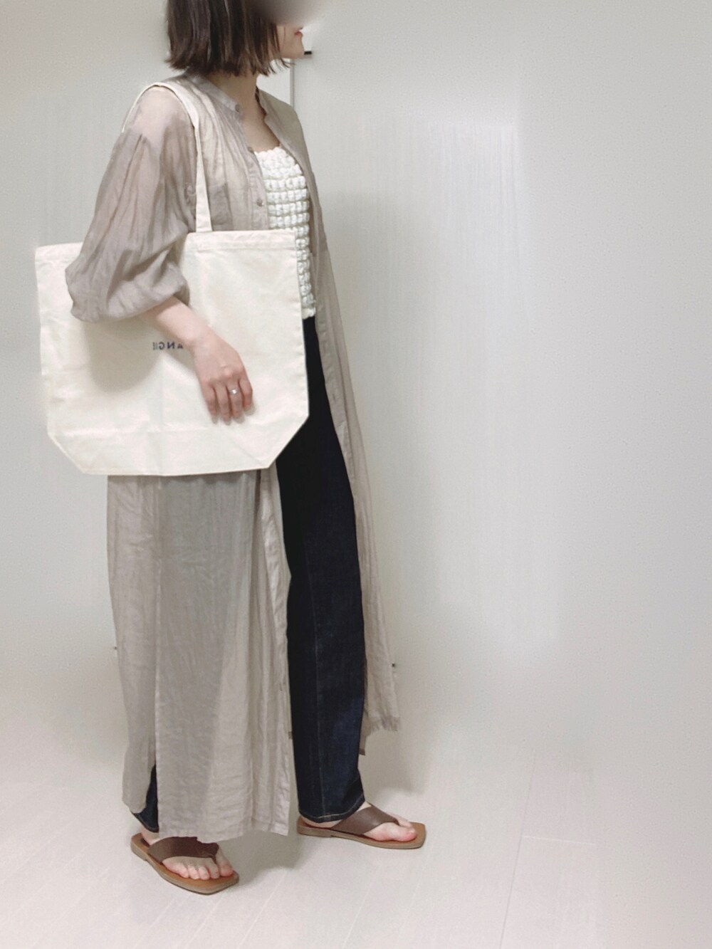 ホワイト系のトートバッグ、ブラウン系のシャツワンピース、ホワイト系のその他トップスを着用したレディースの春コーディネートの2枚目の写真