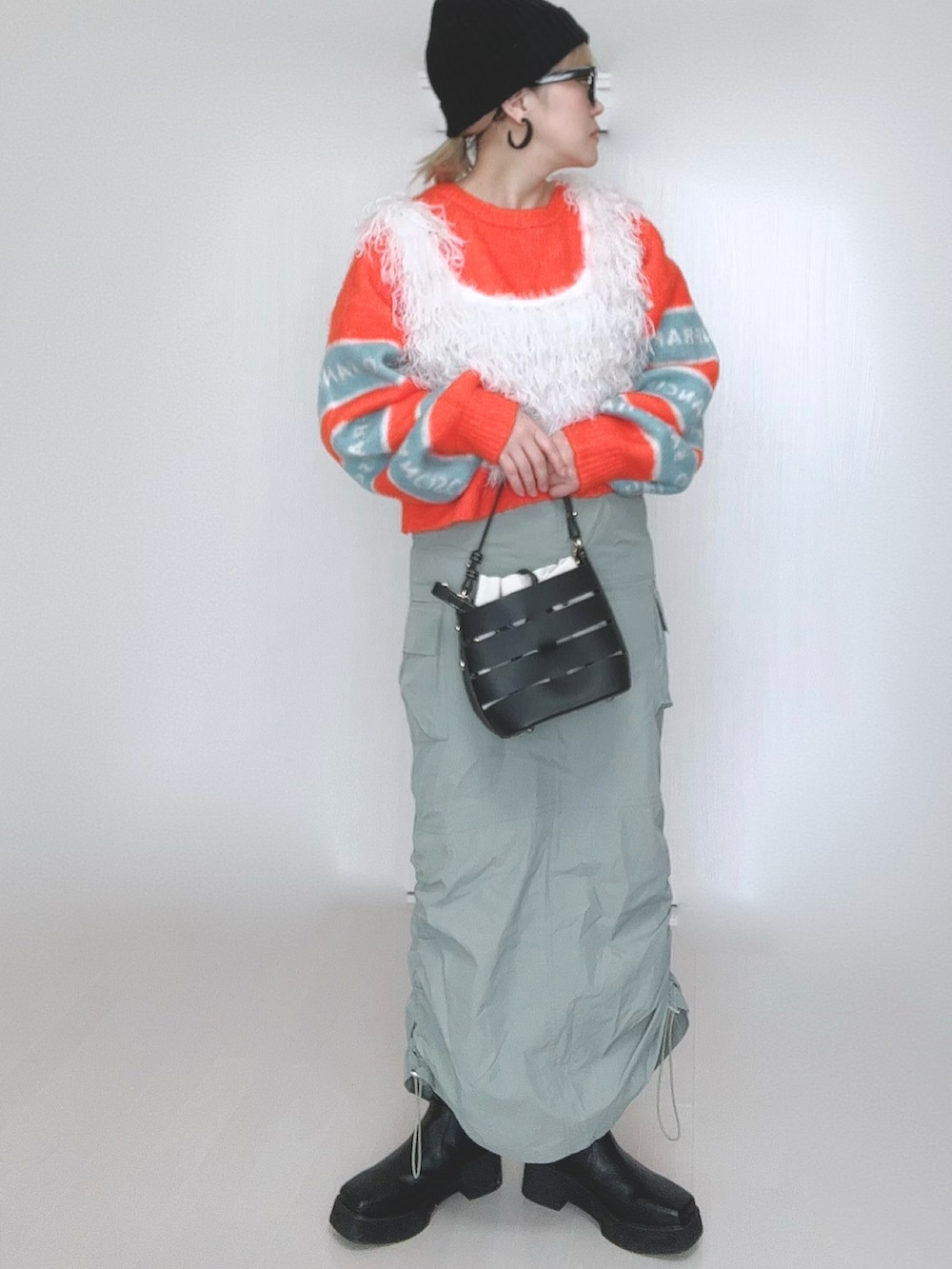 オレンジ系のニット/セーター、ホワイト系のベスト、ブラック系のショルダーバッグを着用したレディースの冬コーディネートの4枚目の写真