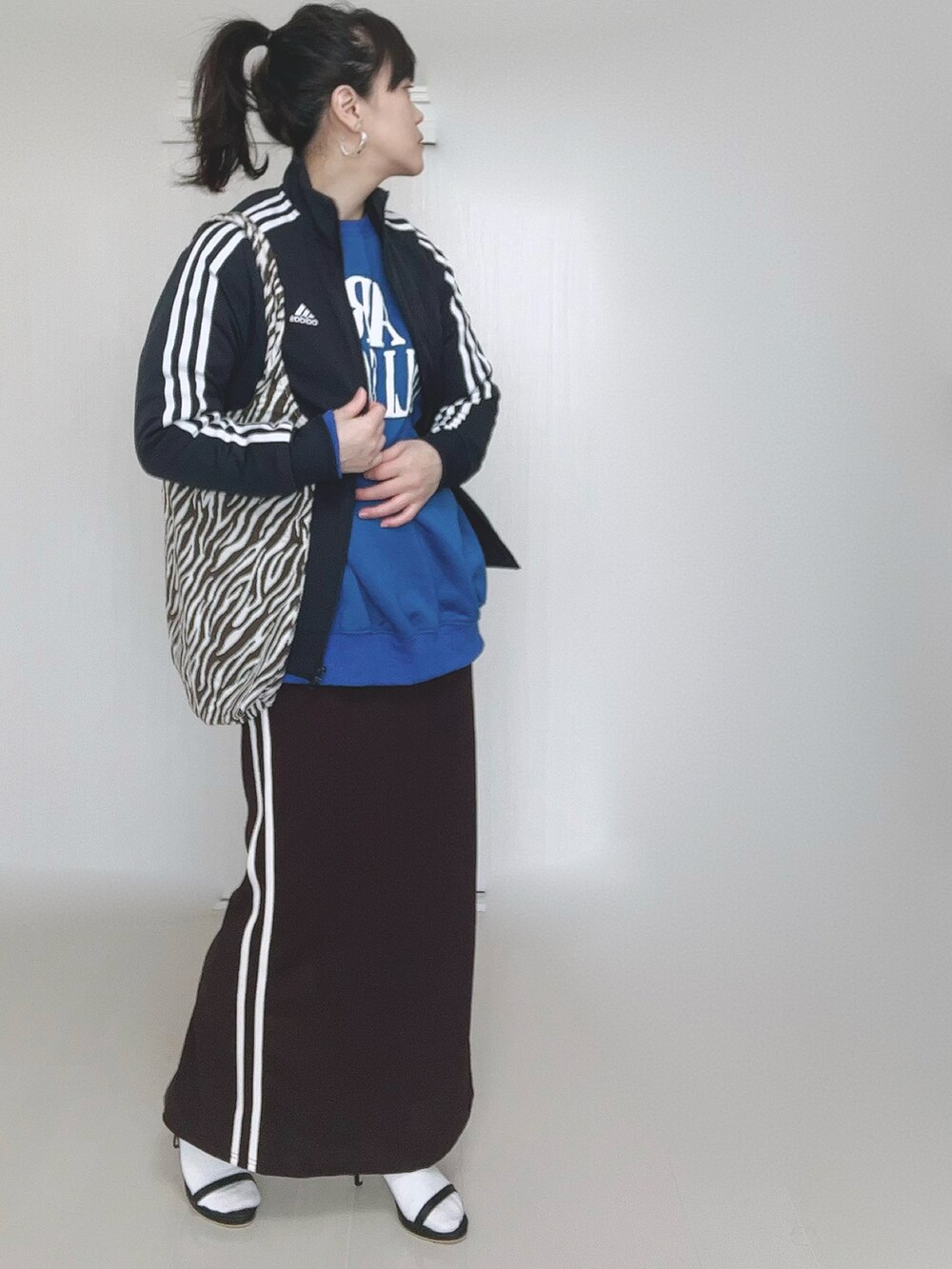 ホワイト系のショルダーバッグ、ブルー系のベスト、ブラック系のサンダルを着用したレディースの冬コーディネートの5枚目の写真