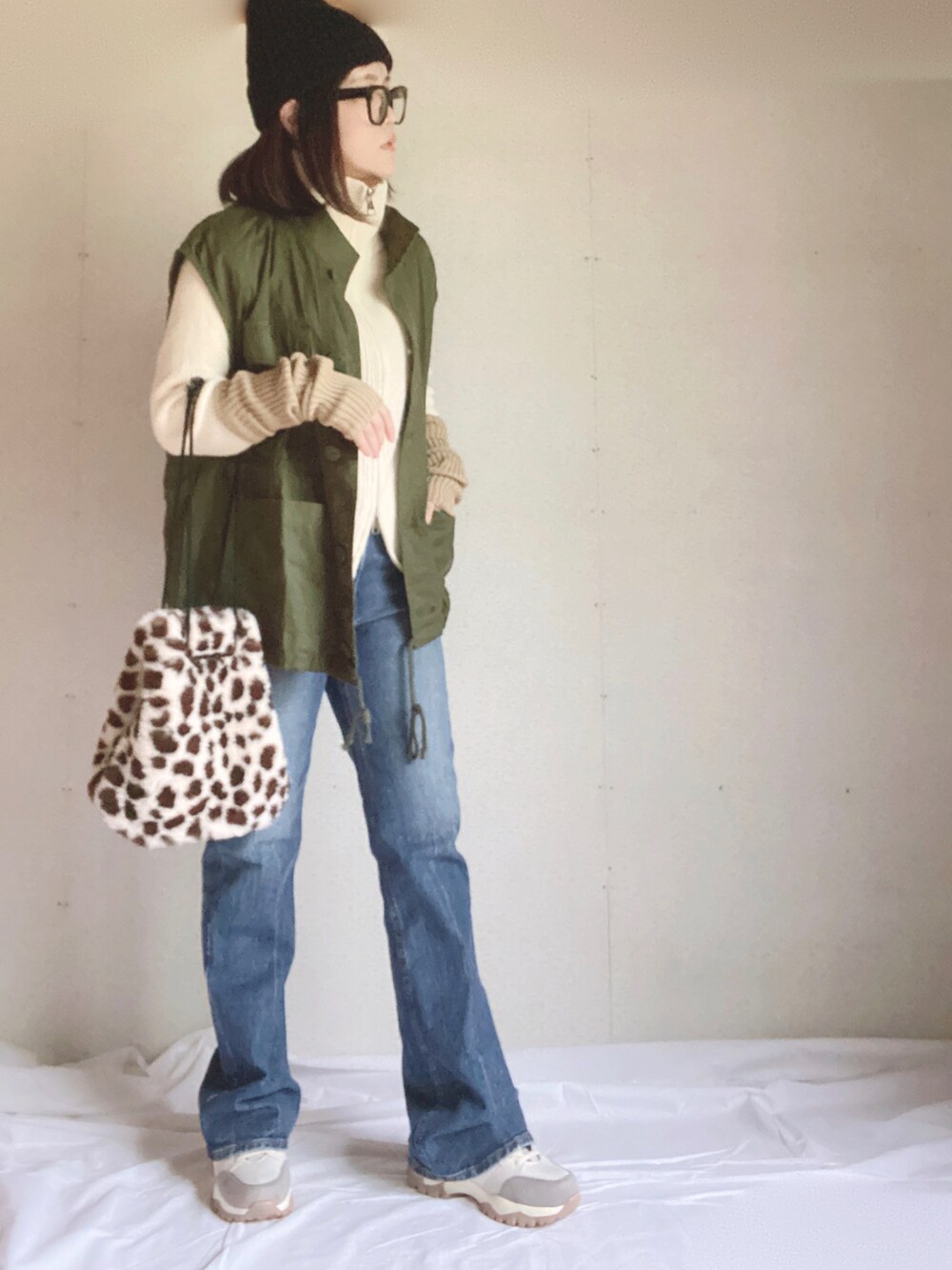 ブルー系のデニムパンツ、ベージュ系のスニーカー、ホワイト系のニット/セーターを着用したレディースの秋コーディネートの5枚目の写真