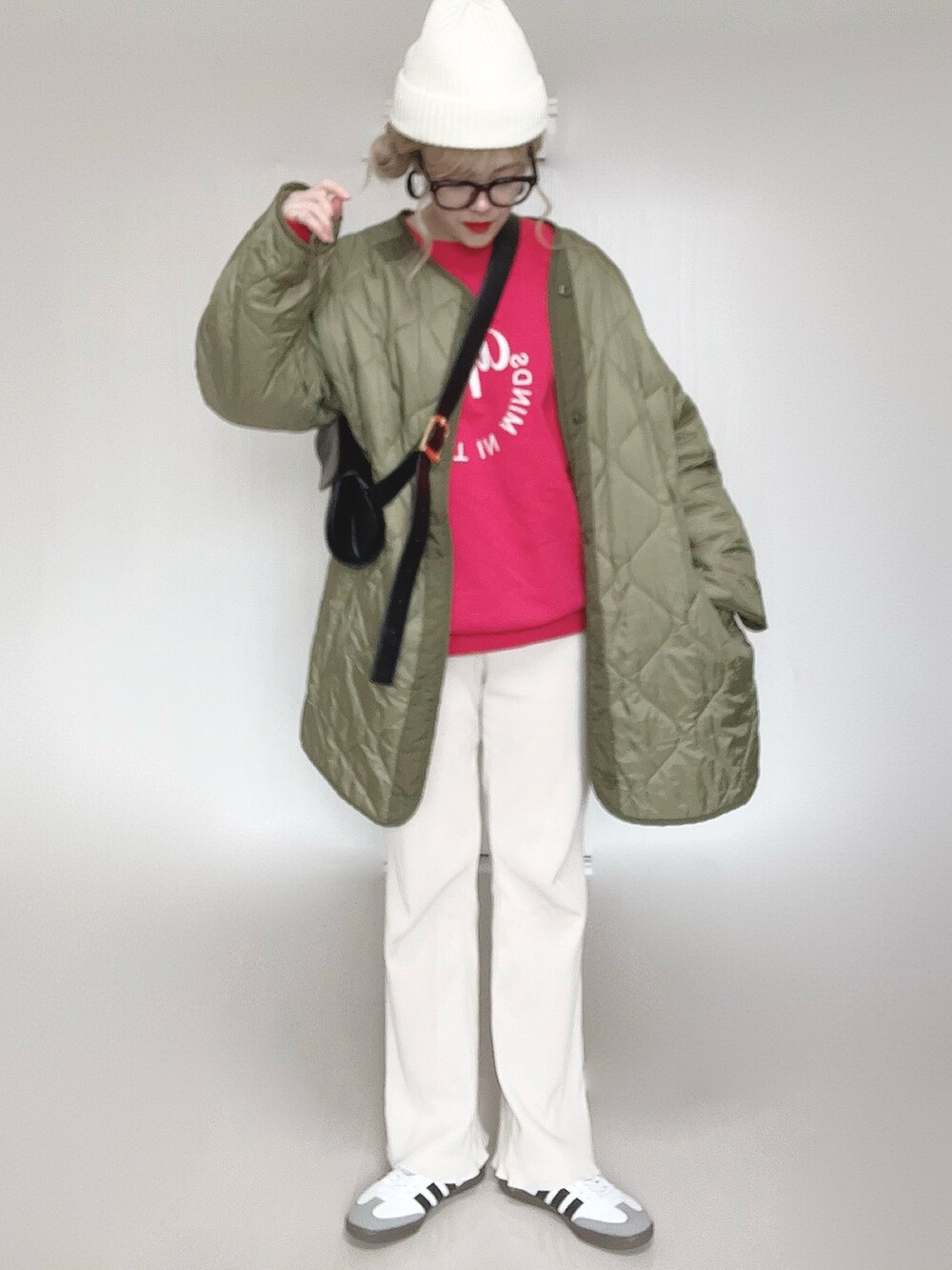 レッド系のスウェット、グリーン系のミリタリージャケット、ホワイト系のその他パンツを着用したレディースの冬コーディネートの3枚目の写真