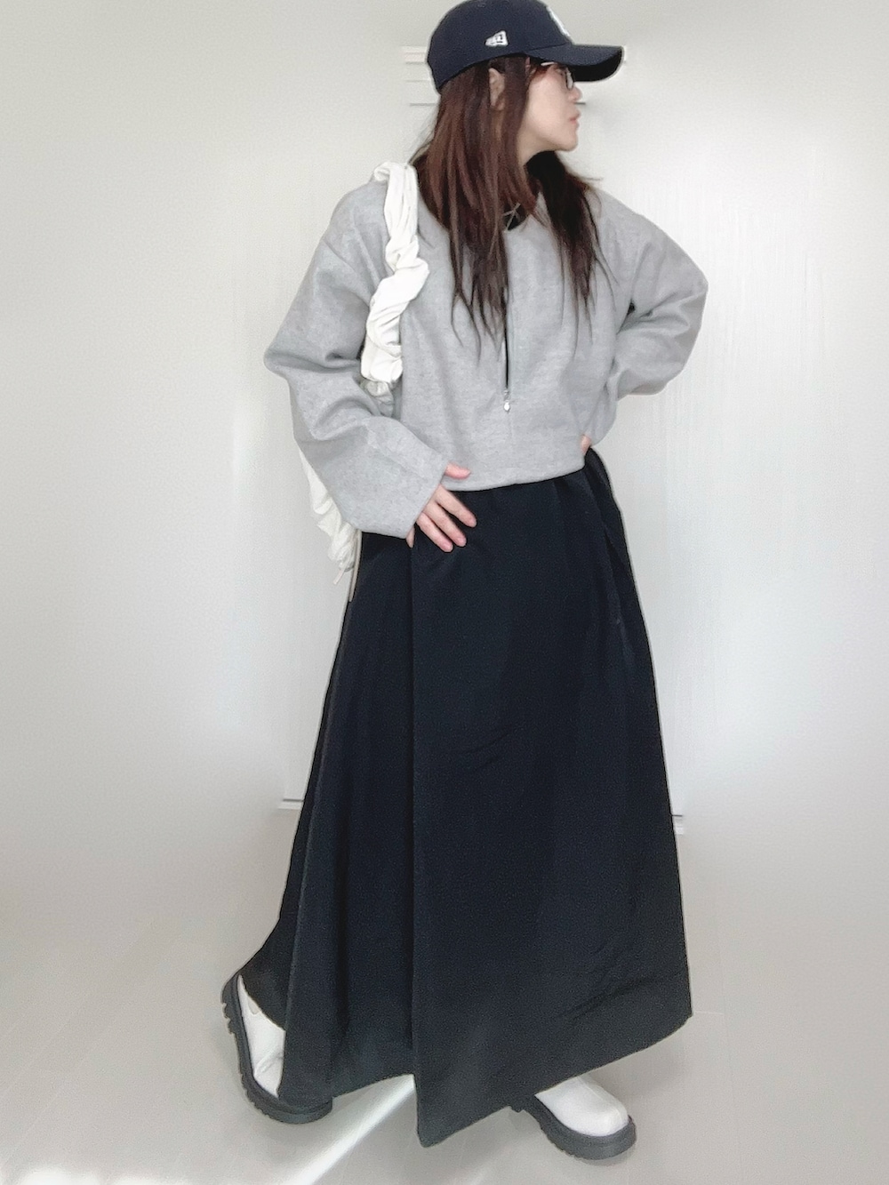 グレー系のワンピース、ホワイト系のショルダーバッグ、ホワイト系のブーツを着用したレディースの秋コーディネートの2枚目の写真