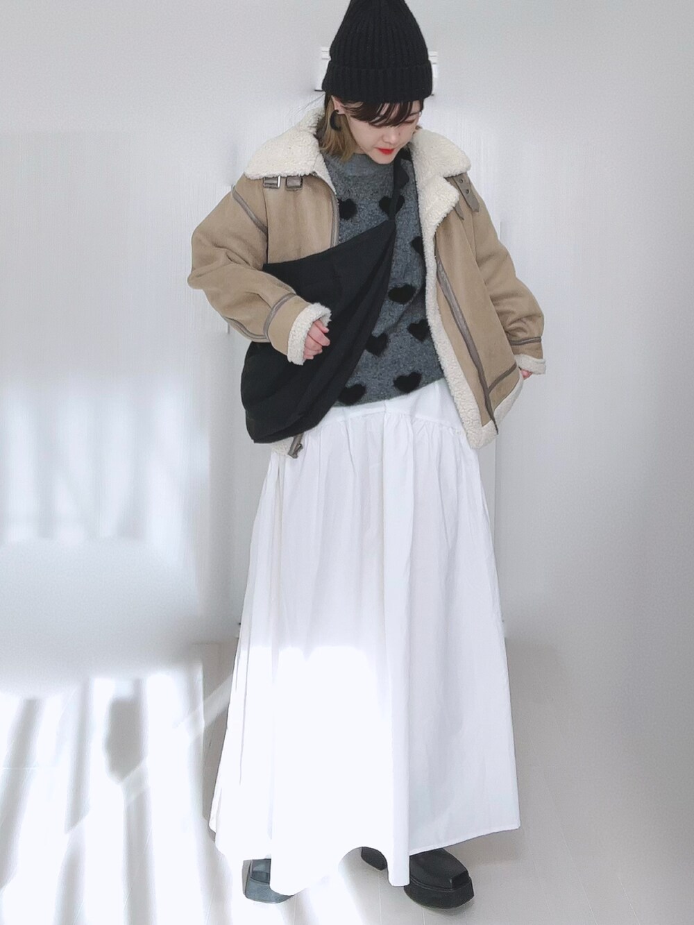 ベージュ系のムートンコート、ホワイト系のスカート、ブラック系のブーツを着用したレディースの冬コーディネートの4枚目の写真
