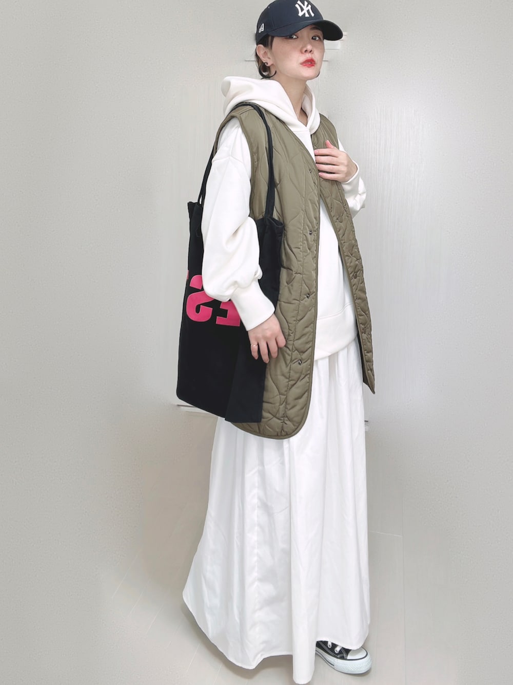 ホワイト系のパーカー、ブラック系のトートバッグ、ホワイト系のスカートを着用したレディースの秋コーディネートの4枚目の写真