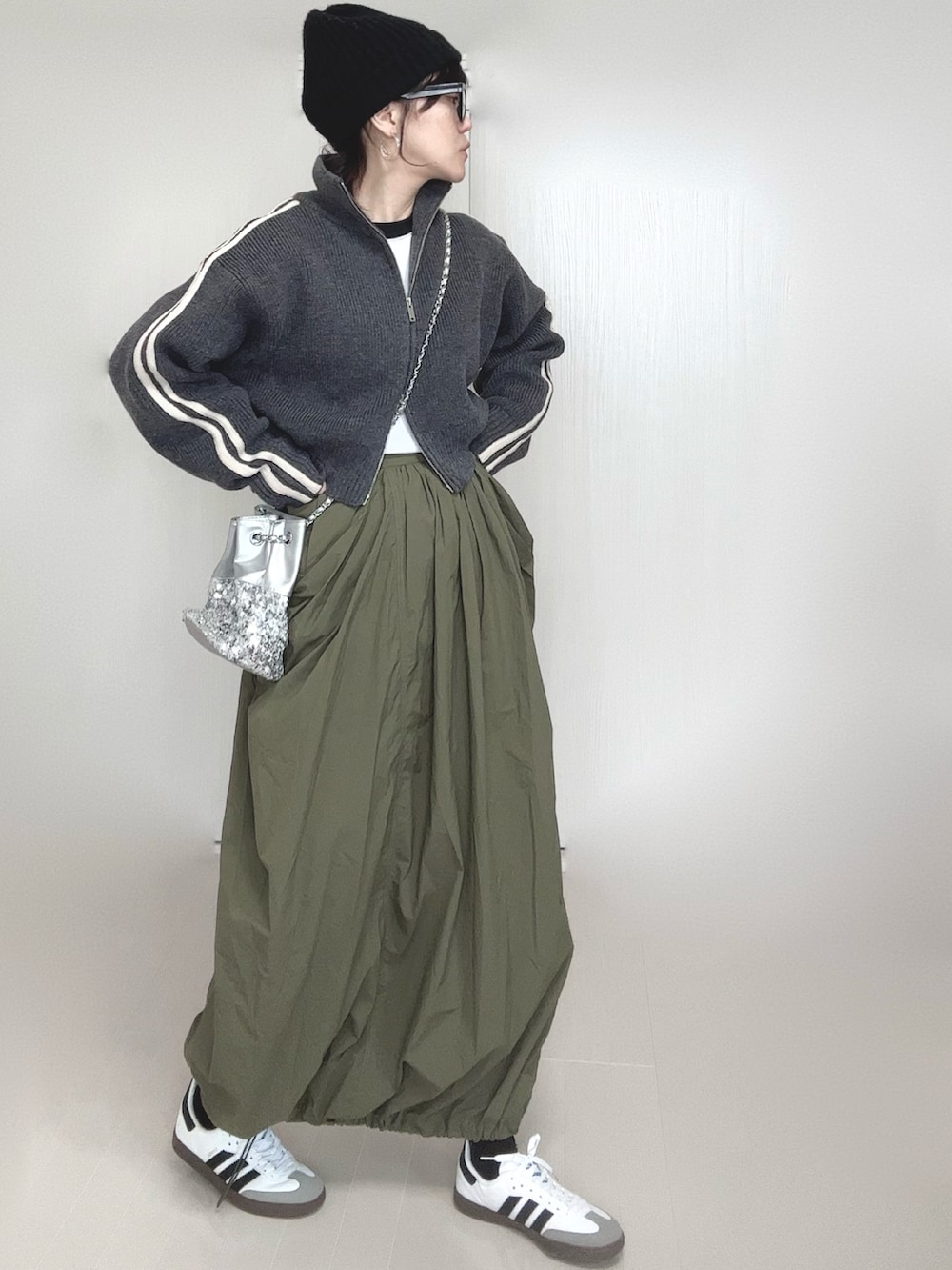 グレー系のニット/セーター、シルバー系のショルダーバッグ、グリーン系のスカートを着用したレディースの冬コーディネートの3枚目の写真