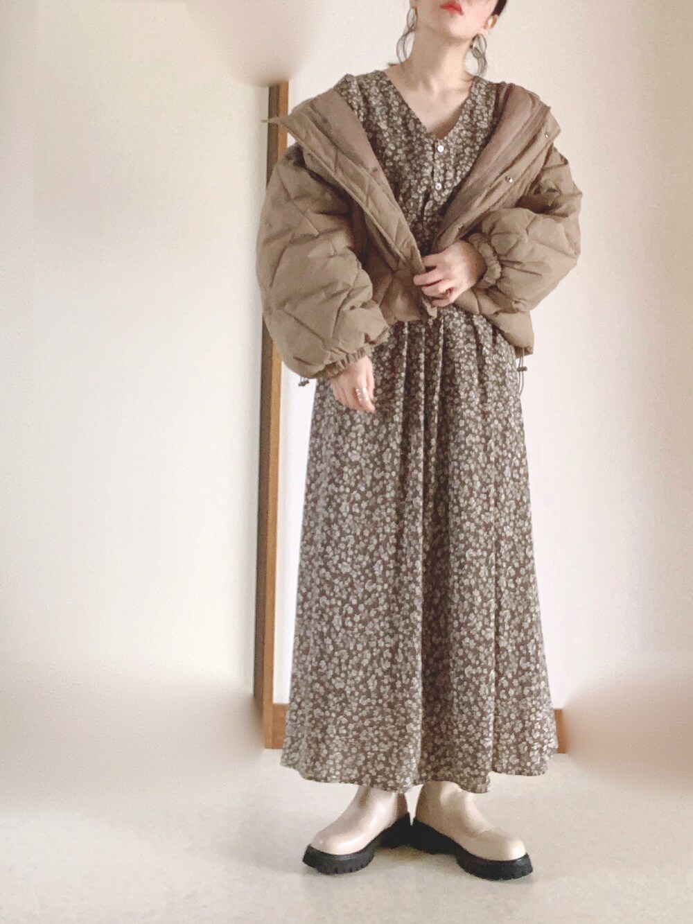 ブラウン系のダウンジャケット/コート、ブラウン系のワンピース、ベージュ系のブーツを着用したレディースの冬コーディネートの2枚目の写真