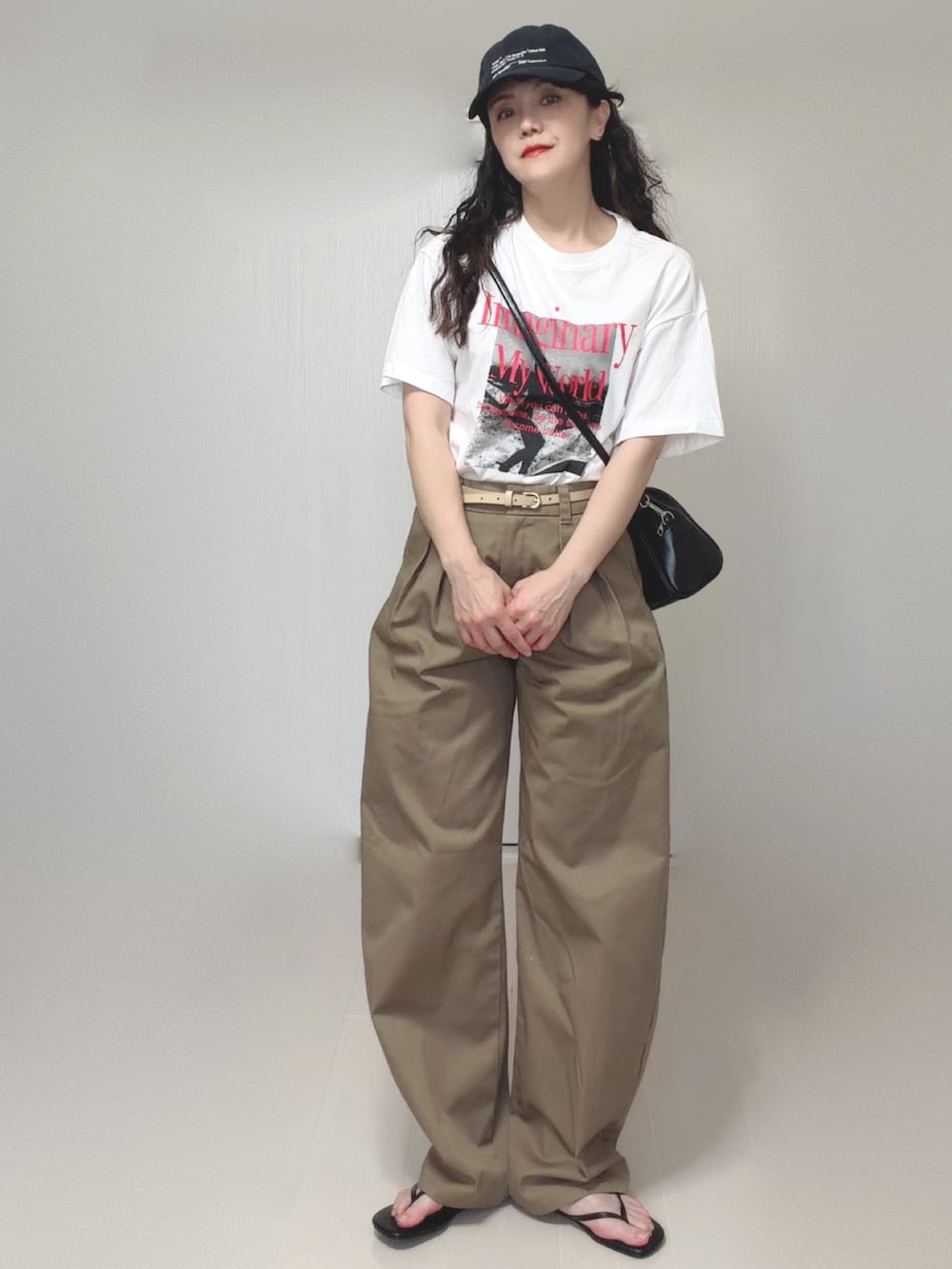 ブラック系のボストンバッグ、ブラック系のサンダル、ベージュ系のチノパンツを着用したレディースの夏コーディネートの3枚目の写真