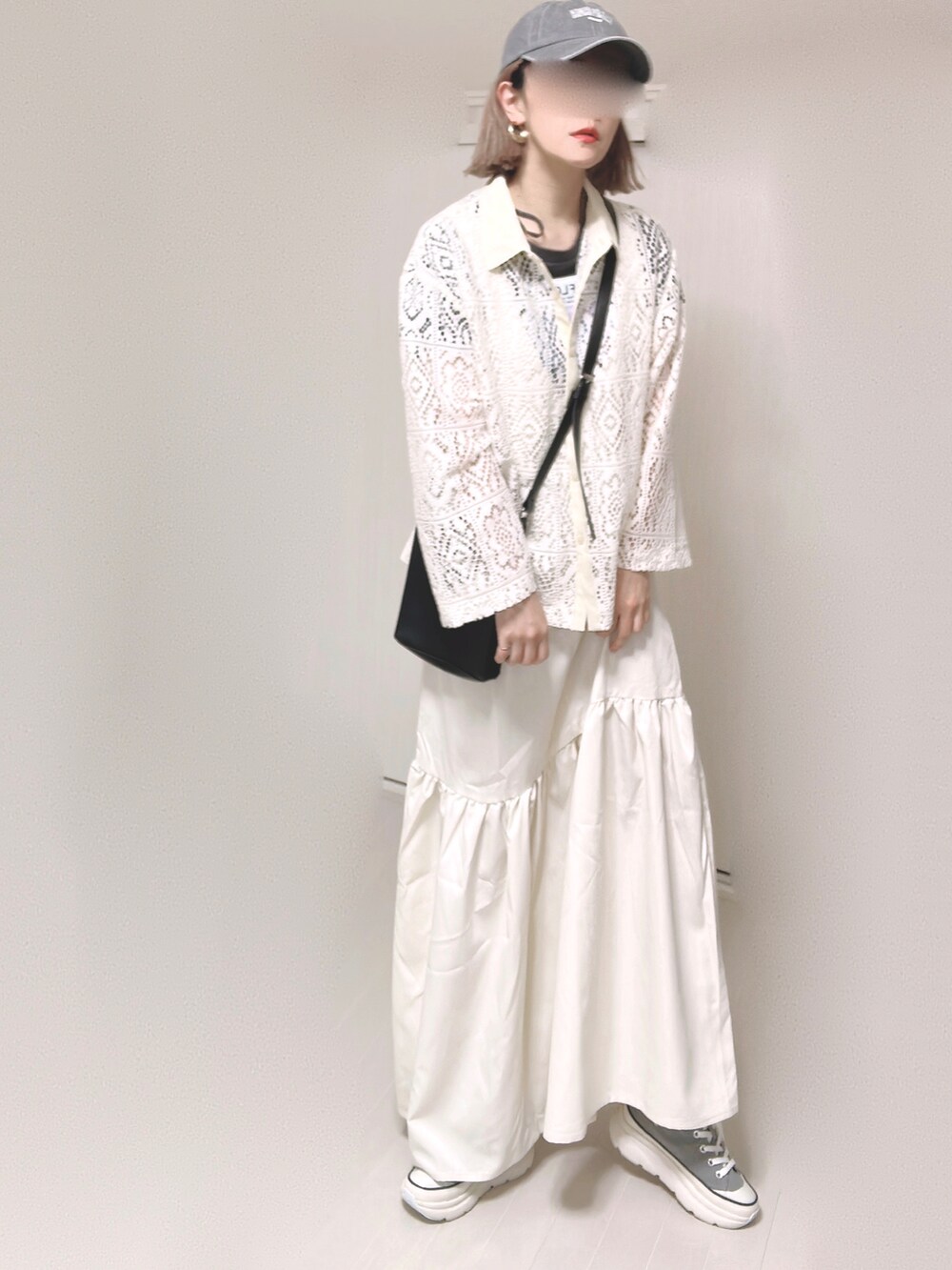 ホワイト系のジャンパースカート、ブラック系のショルダーバッグ、グレー系のスニーカーを着用したレディースの春コーディネートの2枚目の写真