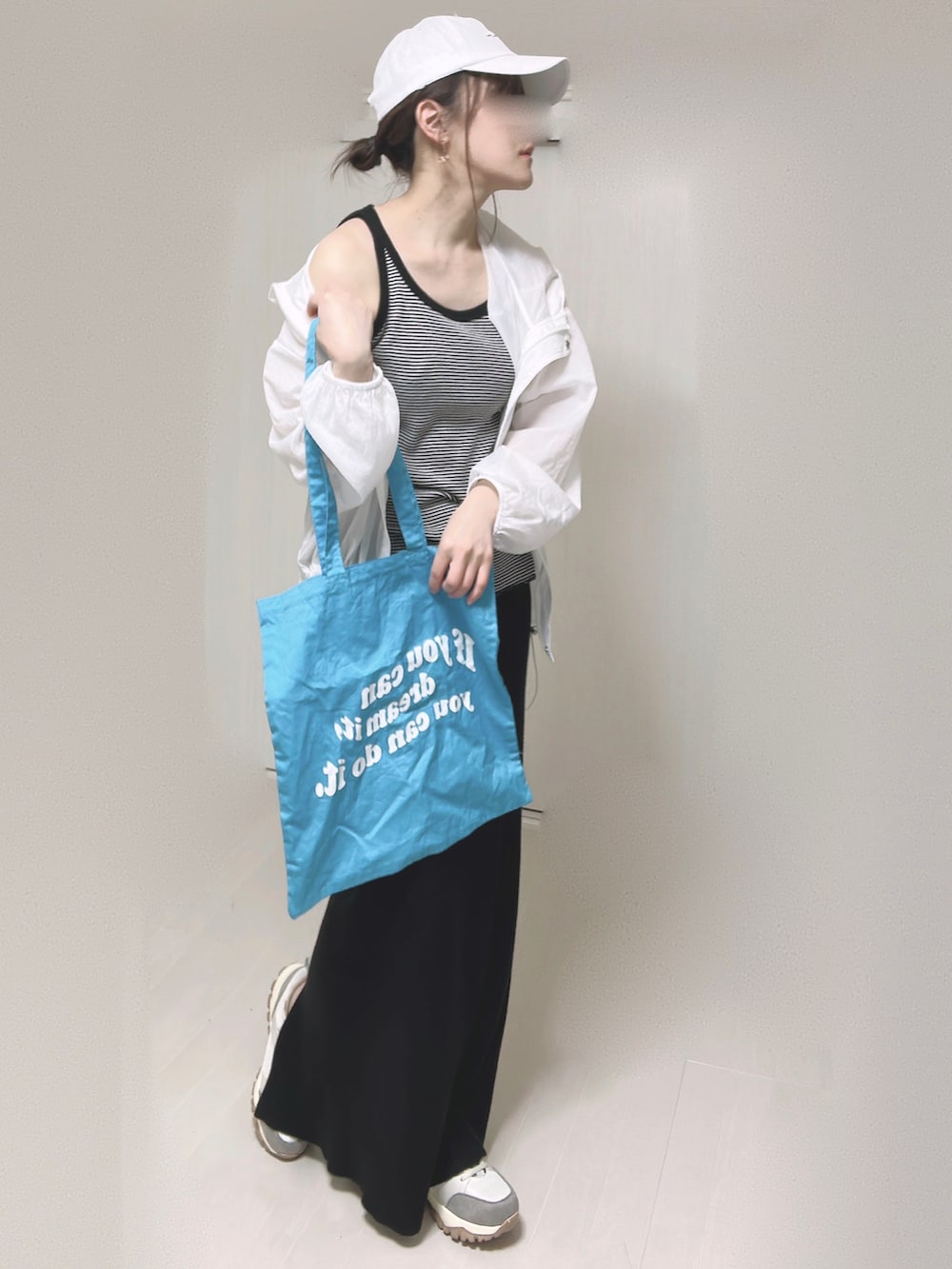 ブラック系のスカート、ブラック系のタンクトップ、ブルー系のトートバッグを着用したレディースの春コーディネートの3枚目の写真