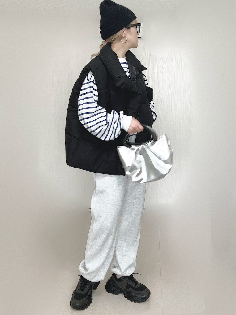 ブラック系のダウンベスト、ブラック系のスニーカー、オレンジ系のニットキャップ/ビーニーを着用したレディースの春コーディネートの2枚目の写真