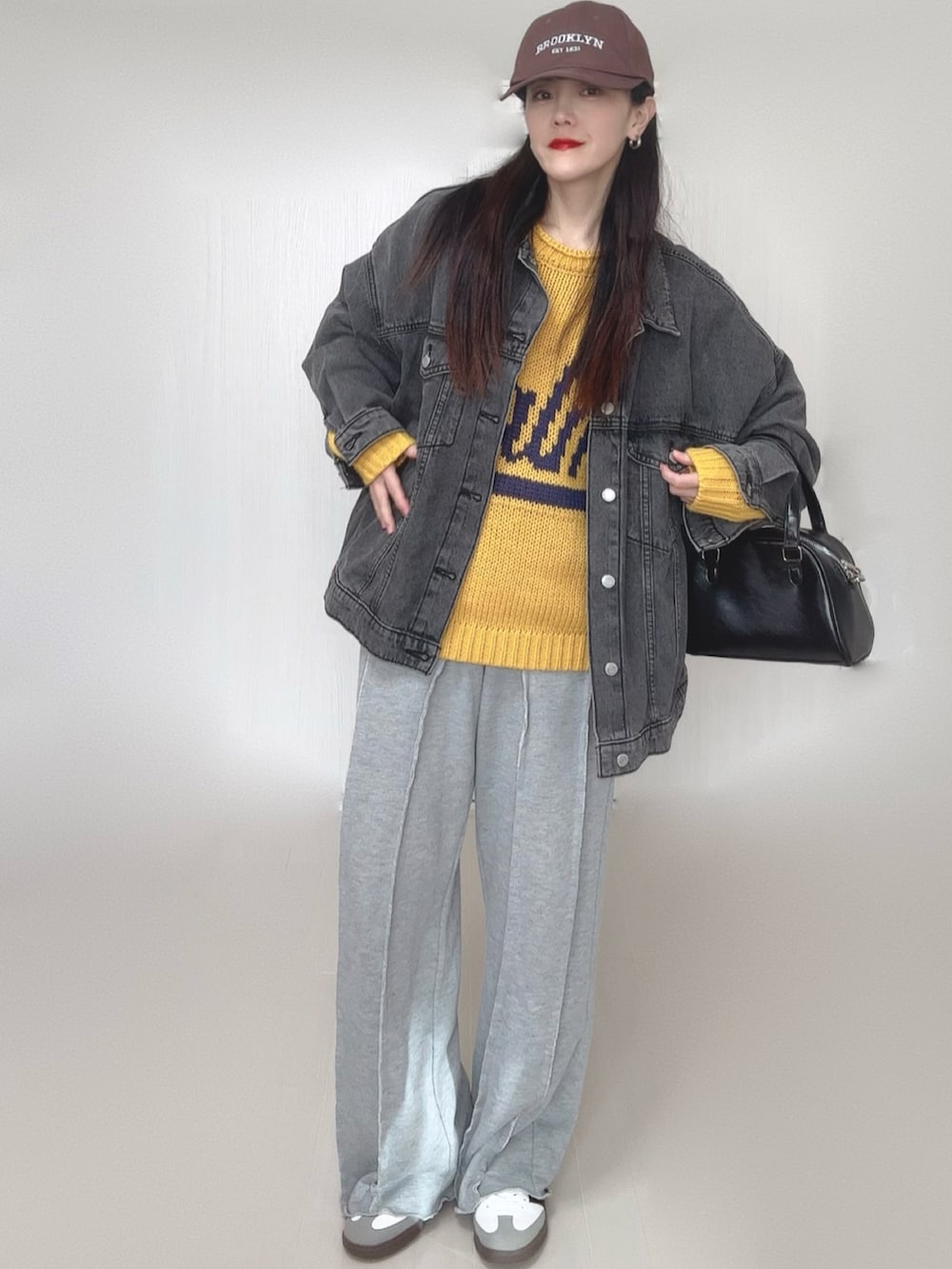 イエロー系のニット/セーター、ブラック系のデニムジャケット、グレー系のスウェットパンツを着用したレディースの冬コーディネートの3枚目の写真