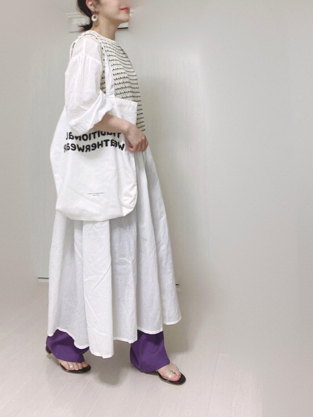 パープル系のスラックス、ホワイト系のシャツワンピース、ホワイト系のトートバッグを着用したレディースの秋コーディネートの2枚目の写真