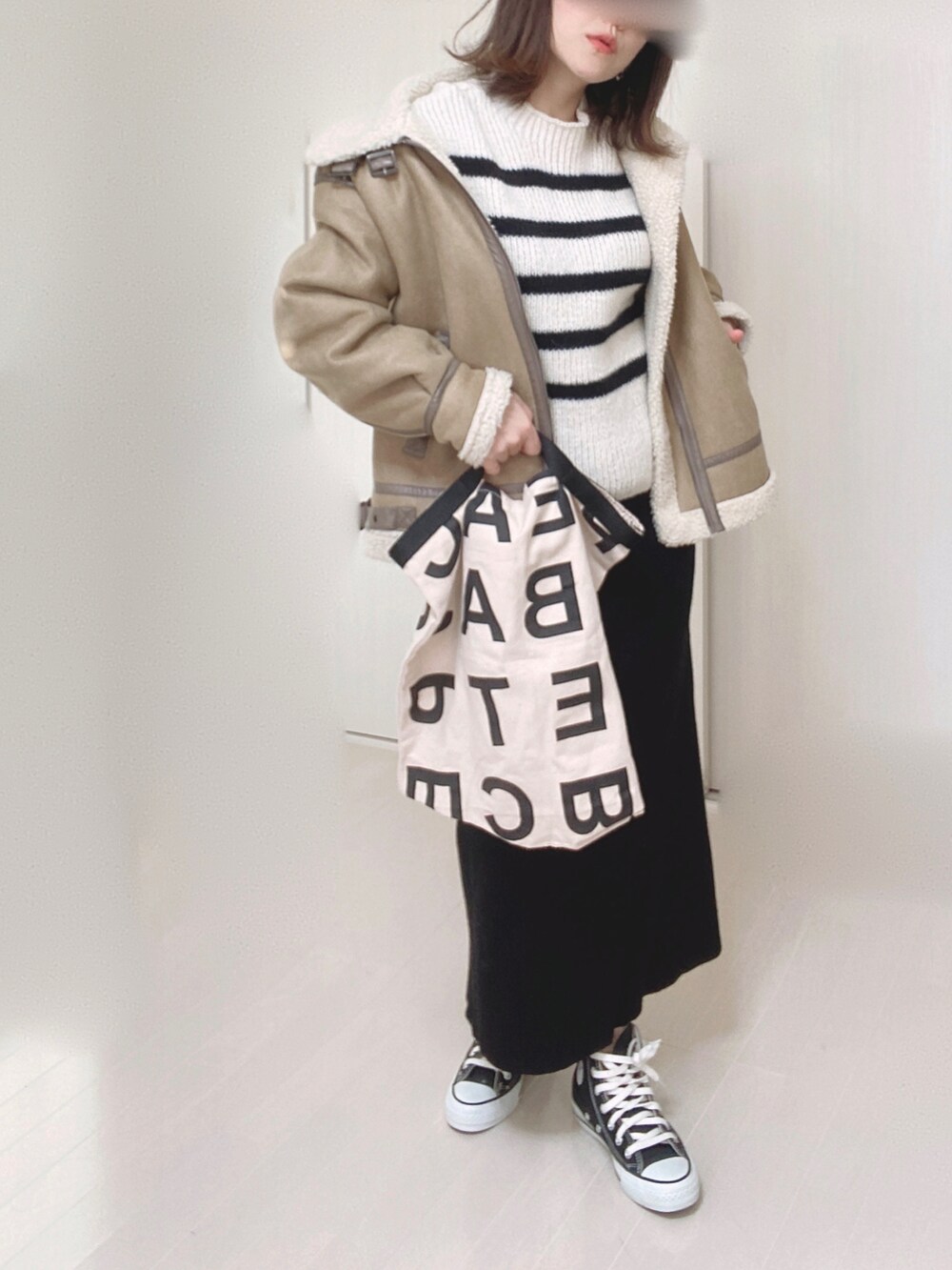 ホワイト系のニット/セーター、ベージュ系のムートンコート、ホワイト系のトートバッグを着用したレディースの冬コーディネートの2枚目の写真
