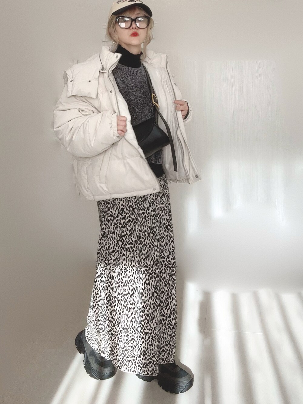 ブラック系のニット/セーター、ブラック系のTシャツ/カットソー、ホワイト系のダウンジャケット/コートを着用したレディースの冬コーディネートの3枚目の写真