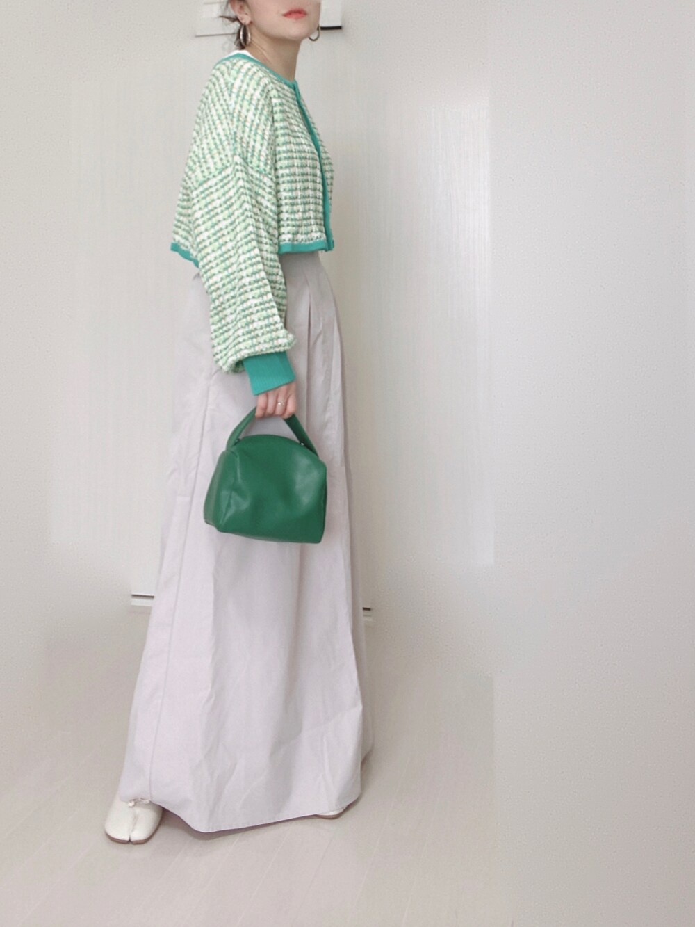 グリーン系のカーディガン/ボレロ、ベージュ系のスカート、グリーン系のハンドバッグを着用したレディースの春コーディネートの2枚目の写真