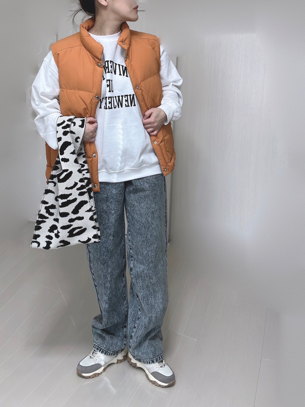 ホワイト系のTシャツ/カットソー、オレンジ系のダウンベスト、ベージュ系のスニーカーを着用したレディースの冬コーディネートの4枚目の写真