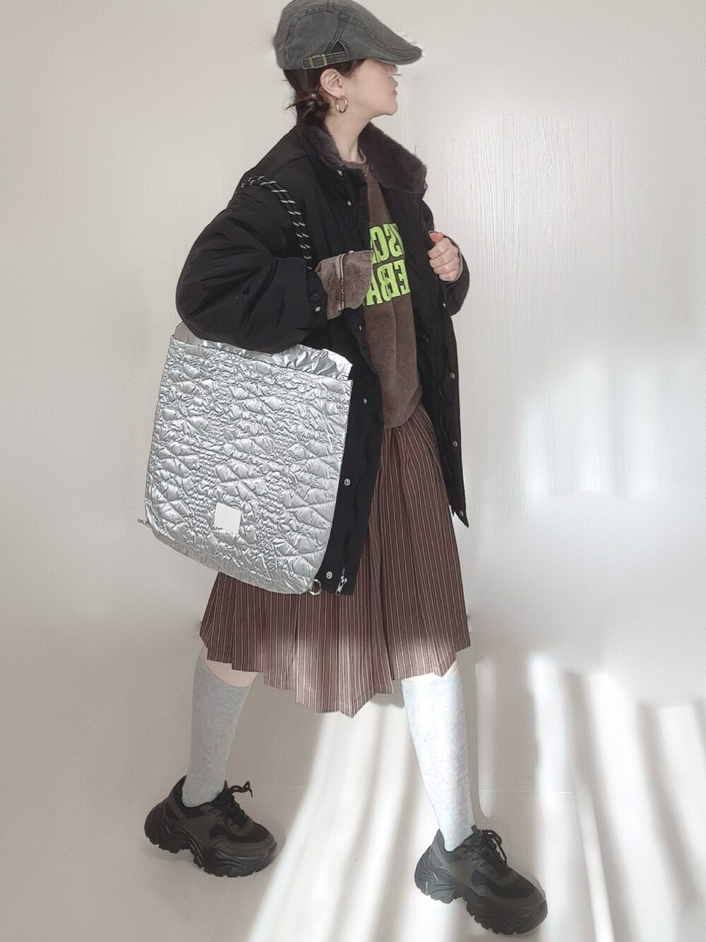 ブラック系のブルゾン、ブラウン系のスウェット、シルバー系のトートバッグを着用したレディースの冬コーディネートの3枚目の写真