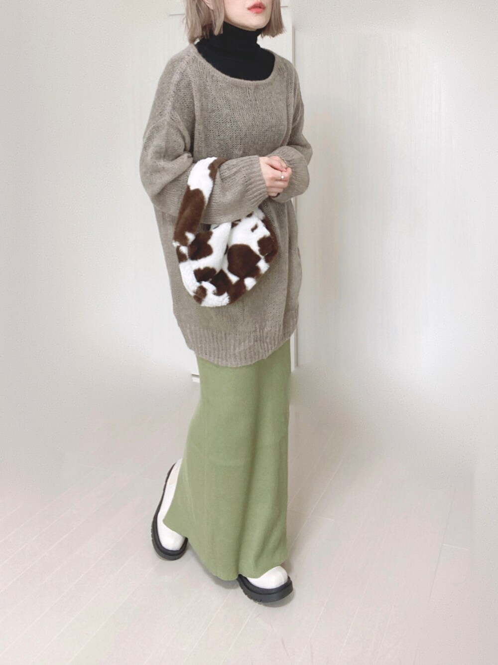 グリーン系のスカート、ベージュ系のニット/セーター、ホワイト系のブーツを着用したレディースの秋コーディネートの3枚目の写真