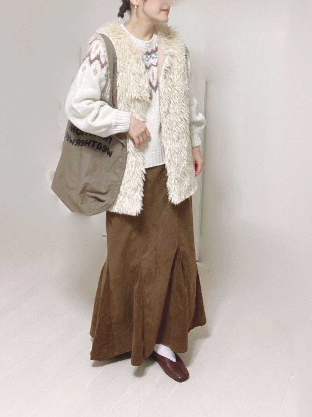 ホワイト系のベスト、ホワイト系のニット/セーター、ブラウン系のスカートを着用したレディースの秋コーディネートの4枚目の写真