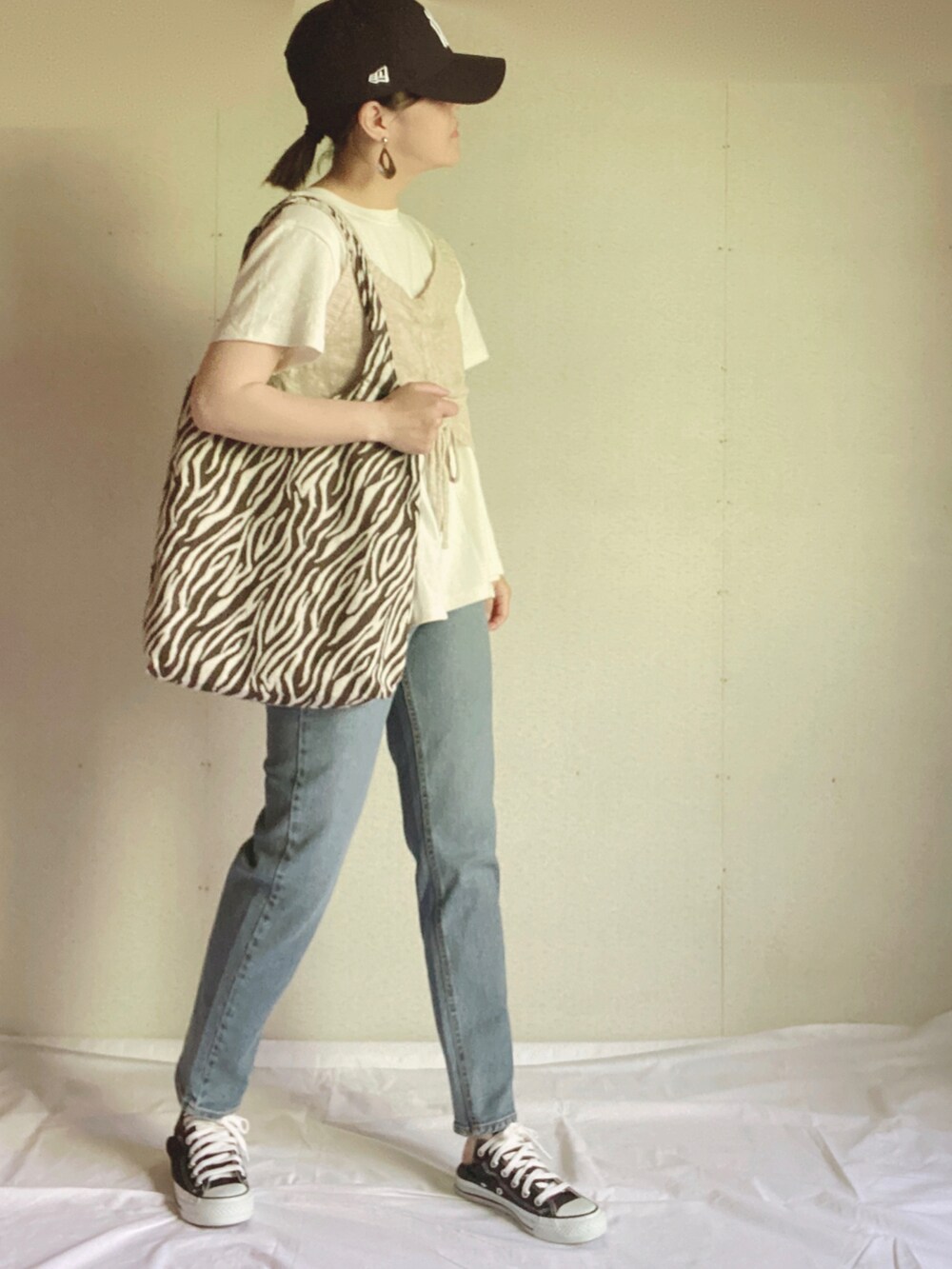 ブルー系のデニムパンツ、ホワイト系のTシャツ/カットソー、ベージュ系のベストを着用したレディースの夏コーディネートの3枚目の写真