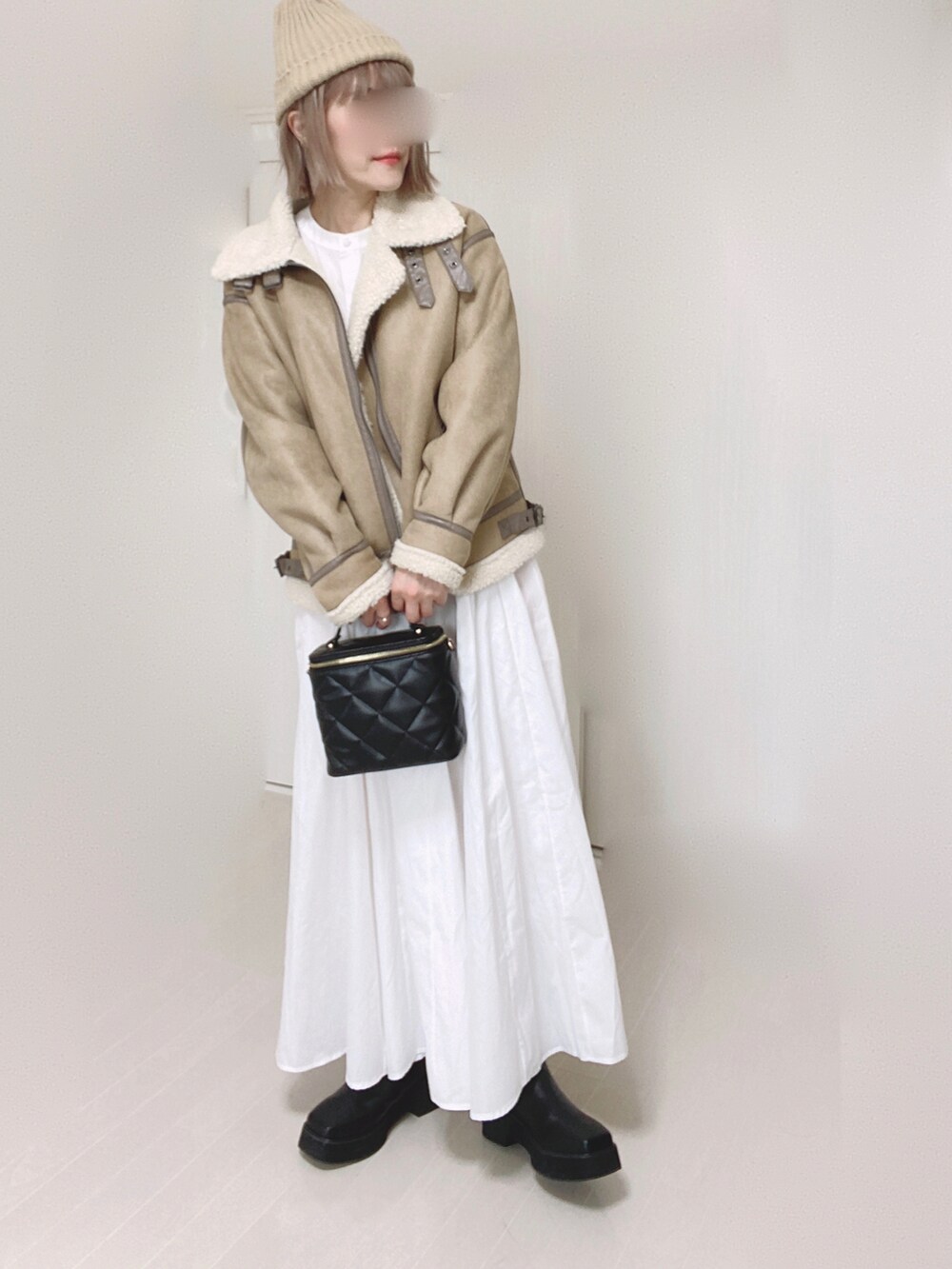 ベージュ系のムートンコート、ホワイト系のシャツワンピース、ブラック系のショルダーバッグを着用したレディースの秋コーディネートの4枚目の写真