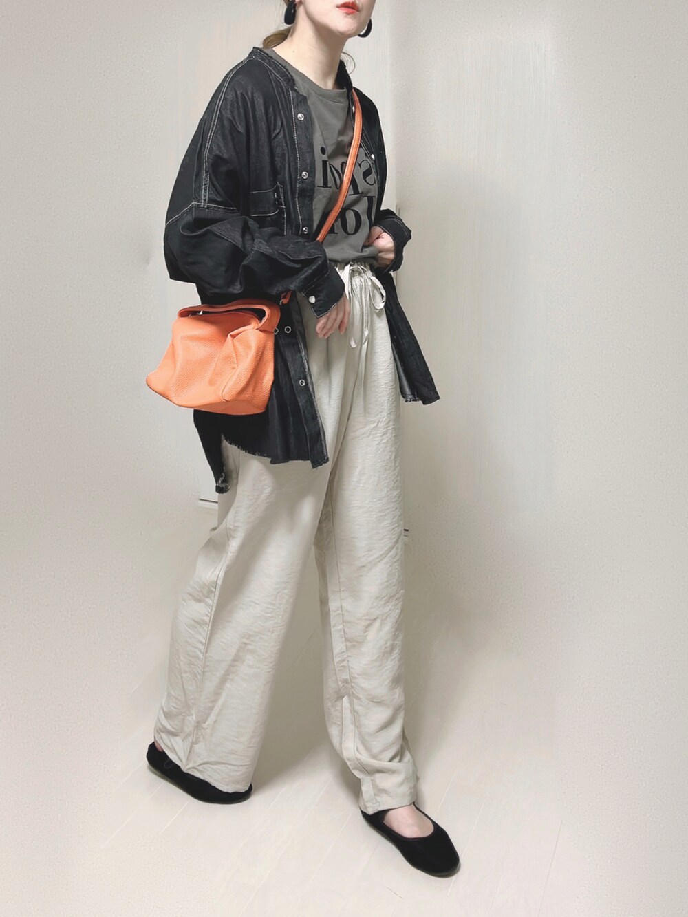 ブラック系のシャツ/ブラウス、オレンジ系のショルダーバッグ、ブラック系のパンプスを着用したレディースの秋コーディネートの2枚目の写真