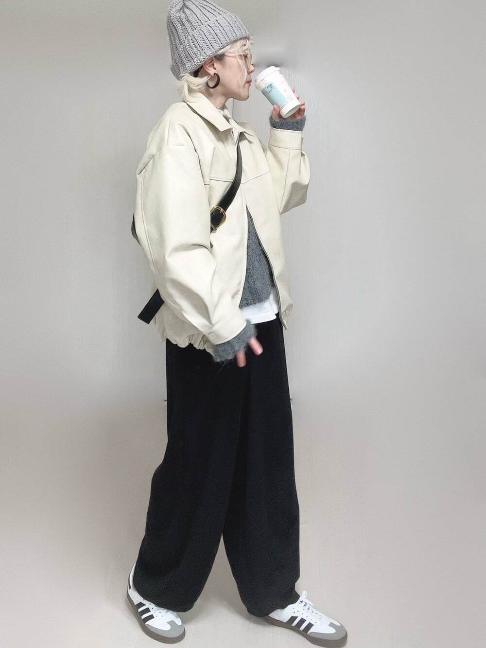 ホワイト系のブルゾン、ホワイト系のTシャツ/カットソー、ブラック系のスラックスを着用したレディースの冬コーディネートの2枚目の写真