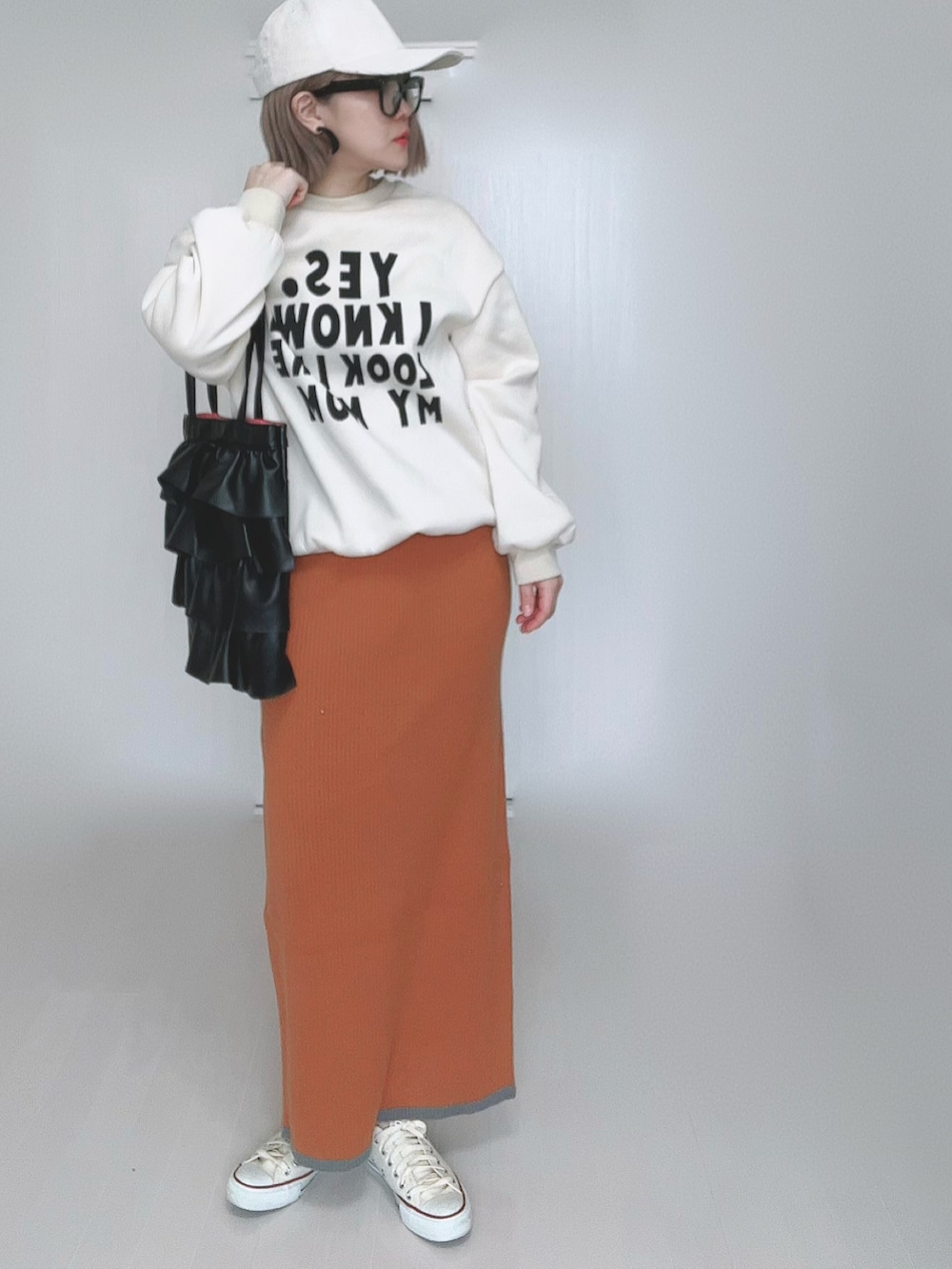 オレンジ系のスカート、ホワイト系のスニーカーを着用したレディースの冬コーディネートの2枚目の写真