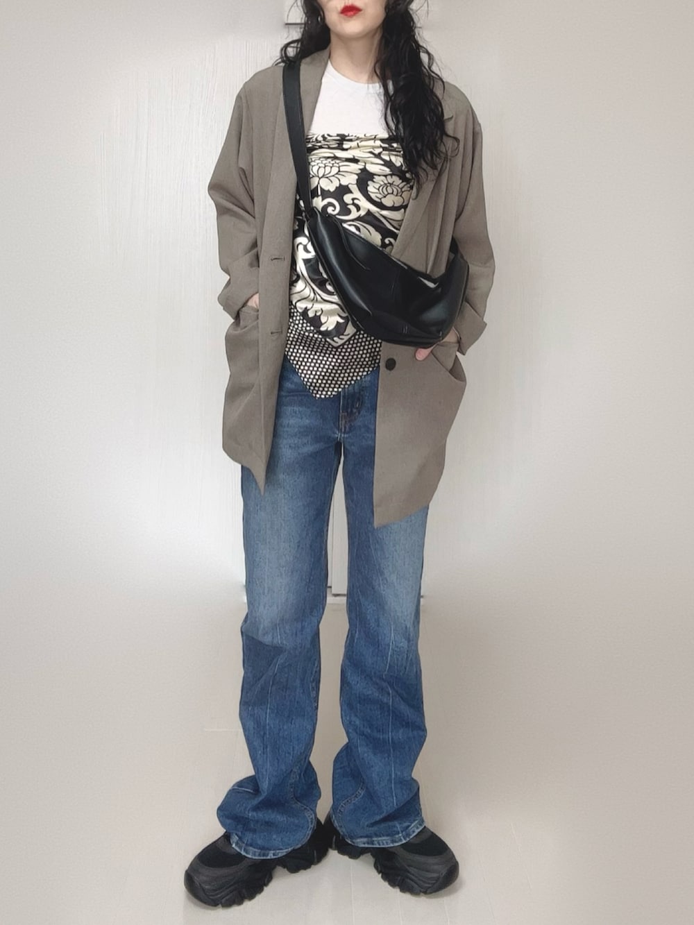 ベージュ系のテーラードジャケット、ブルー系のデニムパンツ、ブラック系のスニーカーを着用したレディースの春コーディネートの2枚目の写真