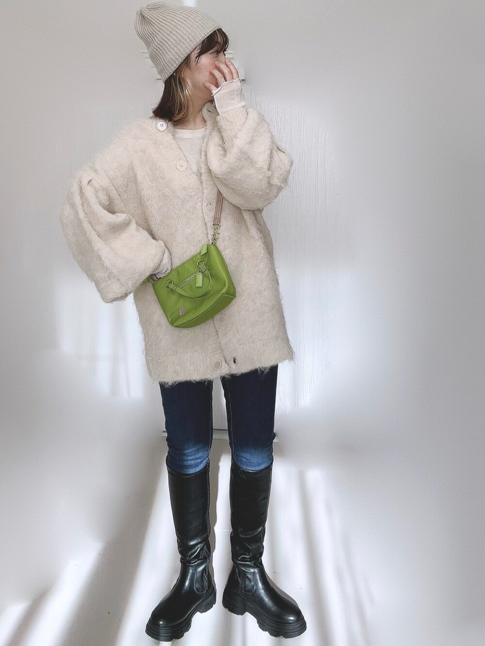 ブラック系のブーツ、ホワイト系のTシャツ/カットソー、ベージュ系のカーディガン/ボレロを着用したレディースの冬コーディネートの5枚目の写真