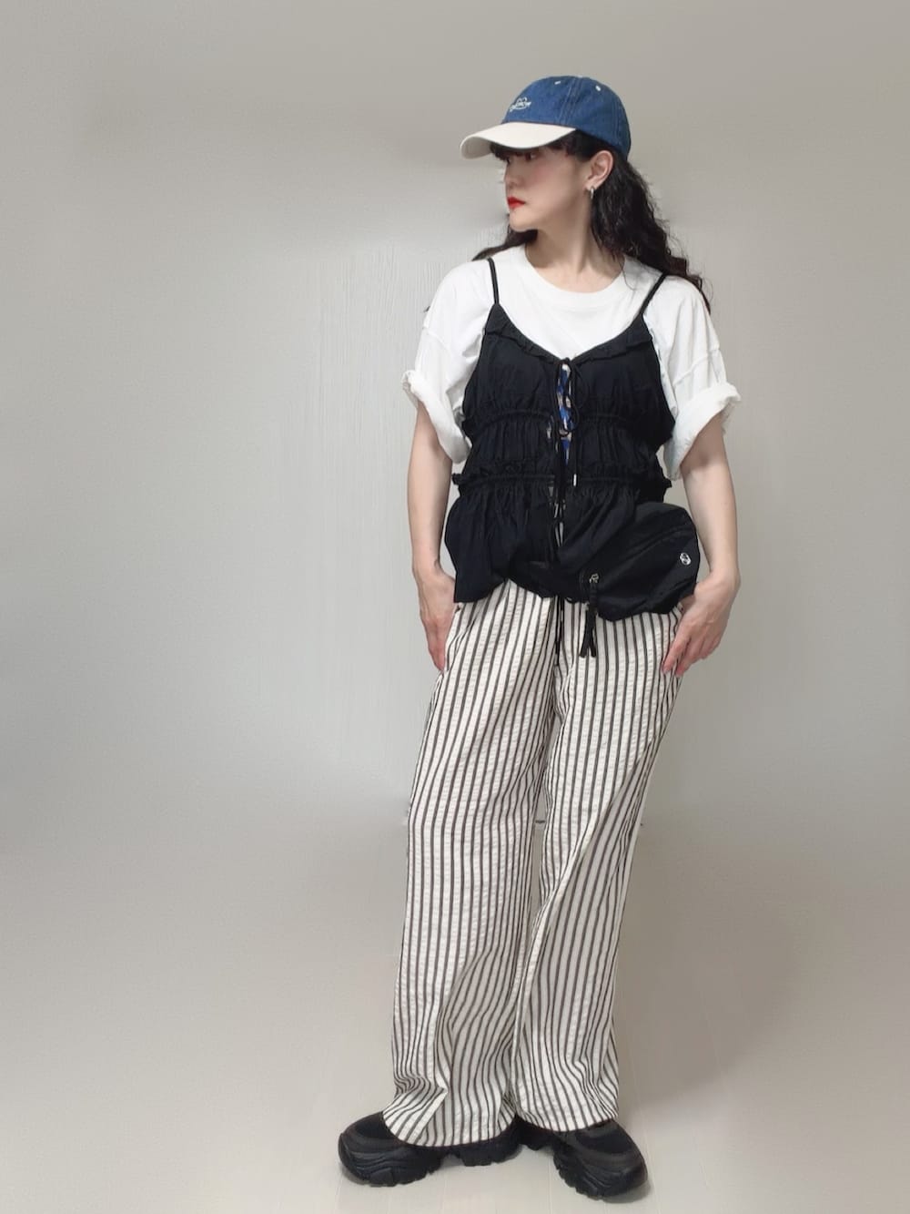 ブラック系のキャミソール、ブラック系のボディバッグ/ウエストポーチ、ホワイト系のTシャツ/カットソーを着用したレディースの夏コーディネートの2枚目の写真