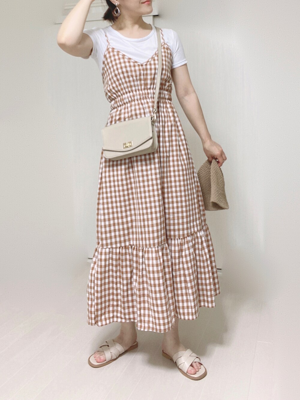 オレンジ系のワンピース、ベージュ系のショルダーバッグ、ホワイト系のサンダルを着用したレディースの夏コーディネートの4枚目の写真