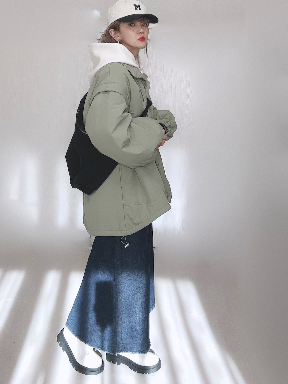 グリーン系のダウンジャケット/コート、ホワイト系のパーカー、ブルー系のセットアップを着用したレディースの冬コーディネートの3枚目の写真