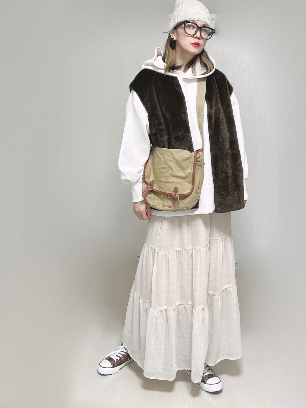 ブラウン系のベスト、ホワイト系のパーカー、ベージュ系のショルダーバッグを着用したレディースの秋コーディネートの4枚目の写真